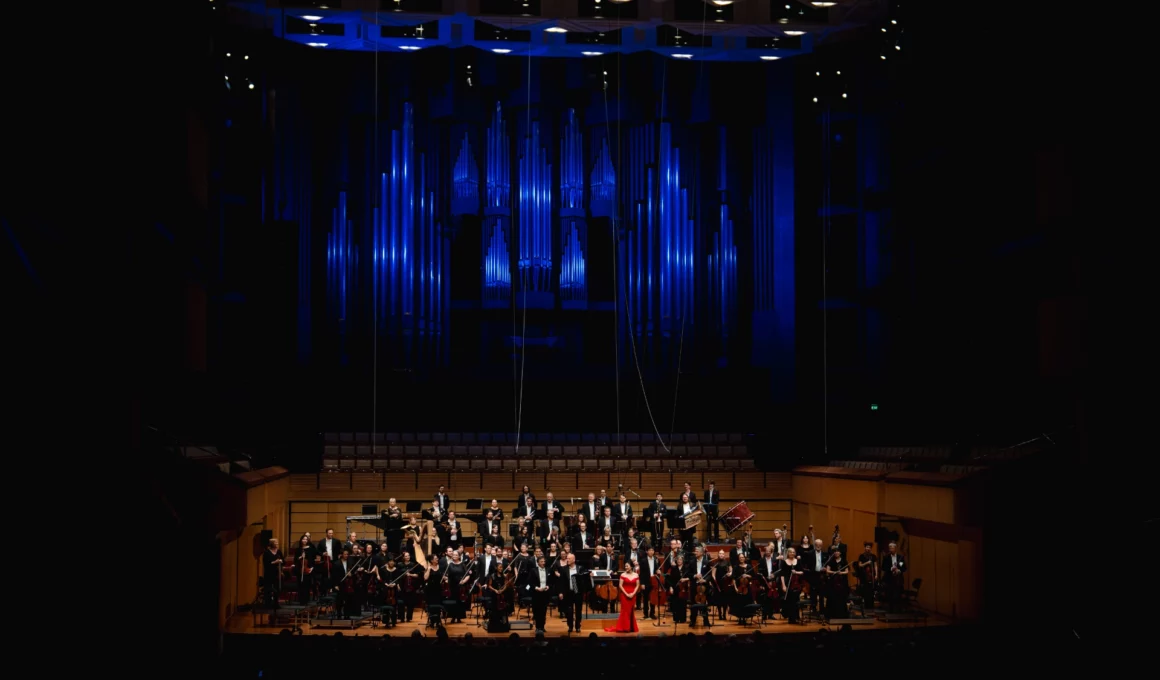 The full Queensland Symphony Orchestra standing on the QPAC Concert Hall stage, accepting a passionate standing ovation and rapturous applause from the audience at the conclusion of the Italian Gala.