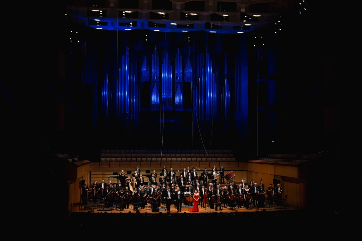 The full Queensland Symphony Orchestra standing on the QPAC Concert Hall stage, accepting a passionate standing ovation and rapturous applause from the audience at the conclusion of the Italian Gala.