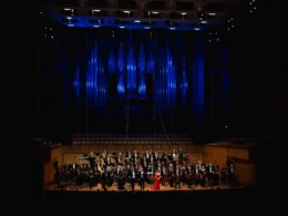 The full Queensland Symphony Orchestra standing on the QPAC Concert Hall stage, accepting a passionate standing ovation and rapturous applause from the audience at the conclusion of the Italian Gala.